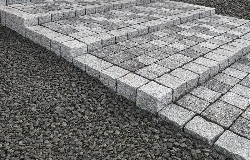 Granitplattor som läggs i mönster med grus runtomkring.